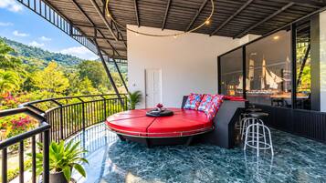 Un área de estar moderna al aire libre con un banco rojo circular, una planta en maceta y vistas de follaje exuberante.