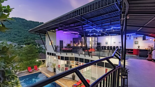 A modern building with a pool, outdoor seating, and a balcony with a TV. - Villa Nap Dau 10 Bedrooms (Chalong)