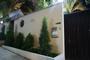 A wall with a clock and a mailbox, surrounded by neatly trimmed bushes. - Tropicale Villa (Rawai)