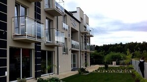 A modern multi-story building with balconies, large windows, and a well-maintained lawn. - Pensjonat Azul (Kolobrzeg)