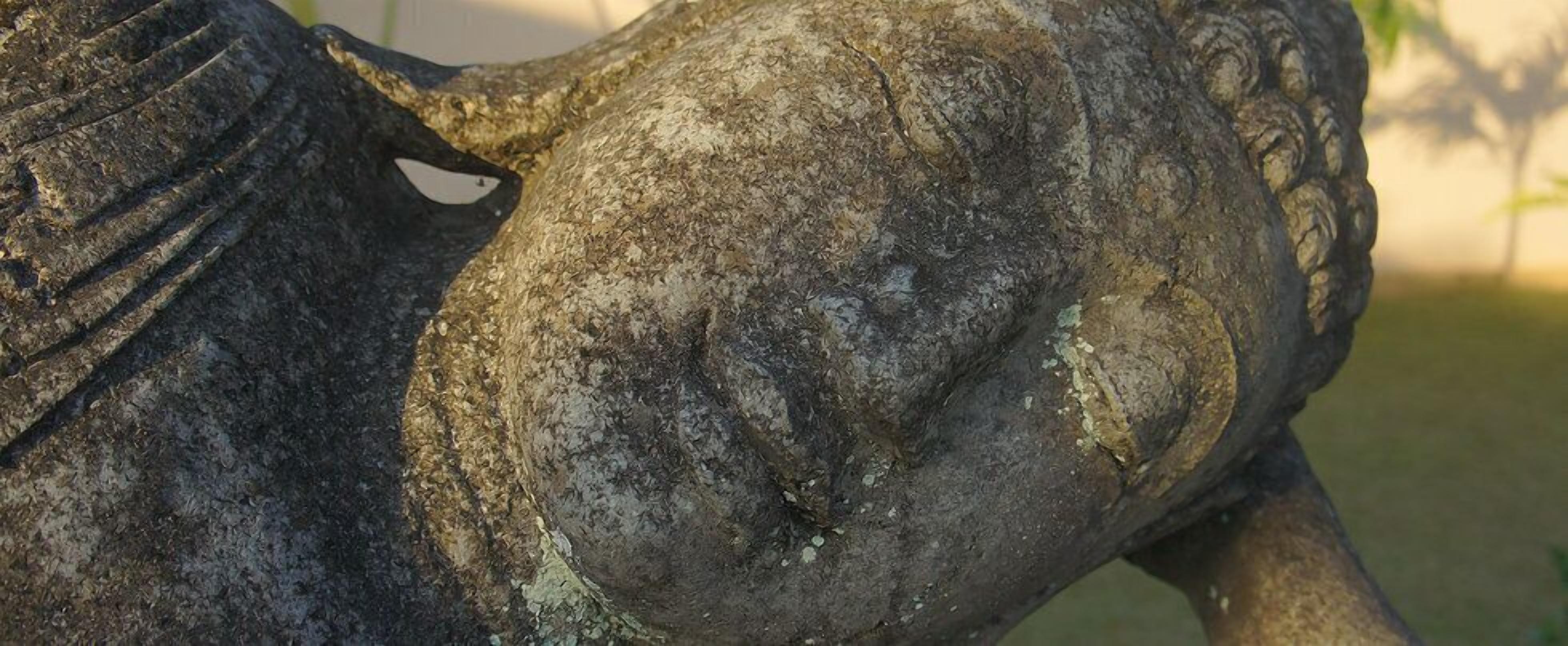 A close-up of a weathered statue with a missing piece.