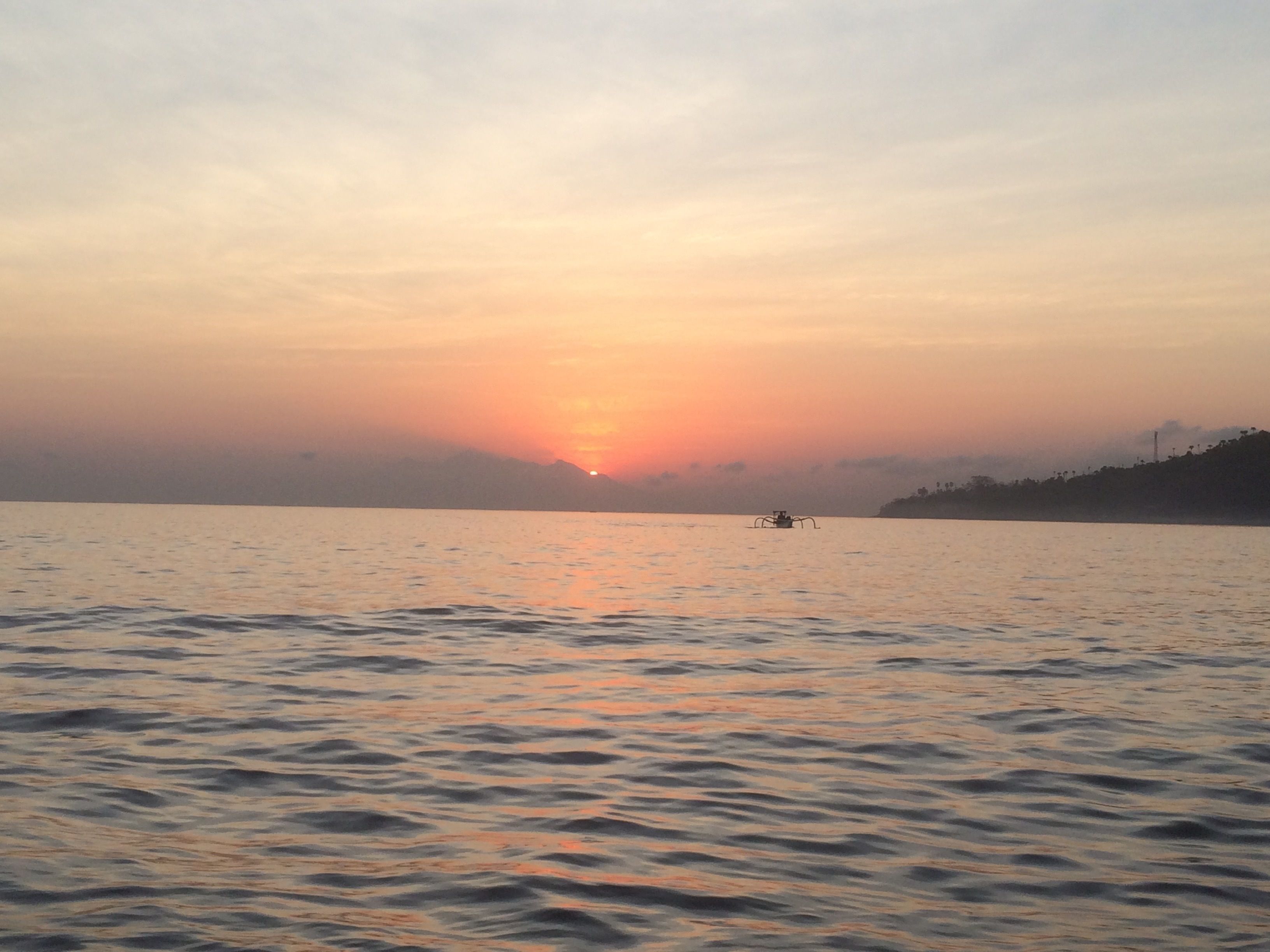A calm lake at sunset with a boat in the distance.