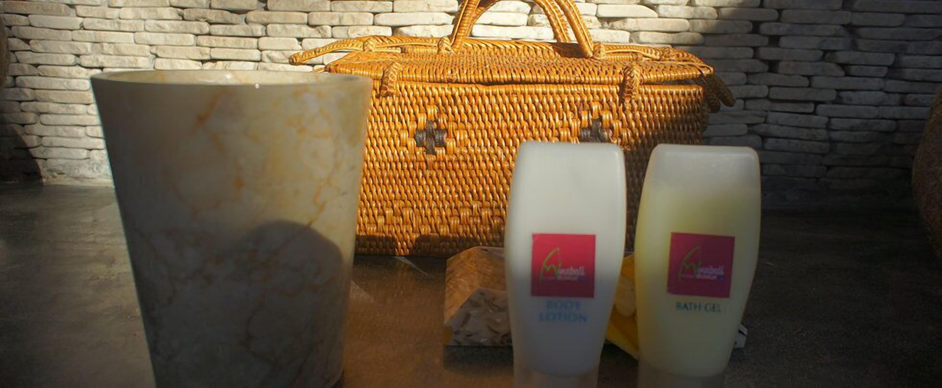 Un panier en osier, un vase en marbre et deux flacons de lotion pour le corps et de gel douche.