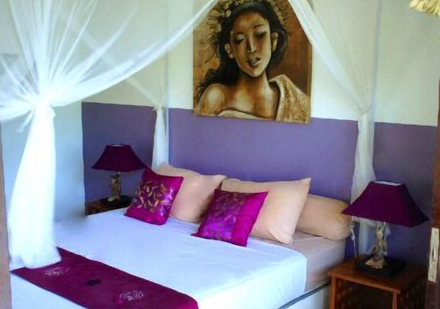 Una cama con dosel, almohadas moradas y un cuadro en la pared superior.