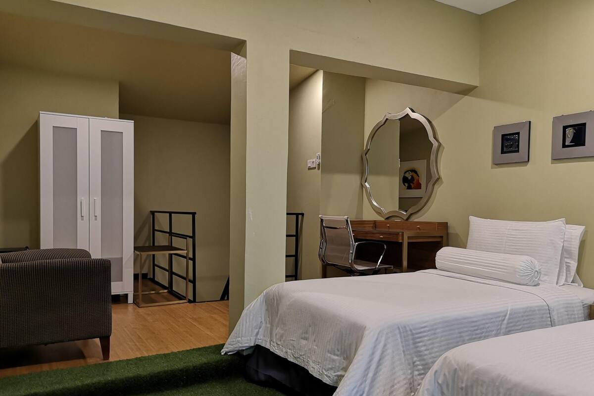 A bedroom with two beds, a wardrobe, a desk, a chair, and a mirror.