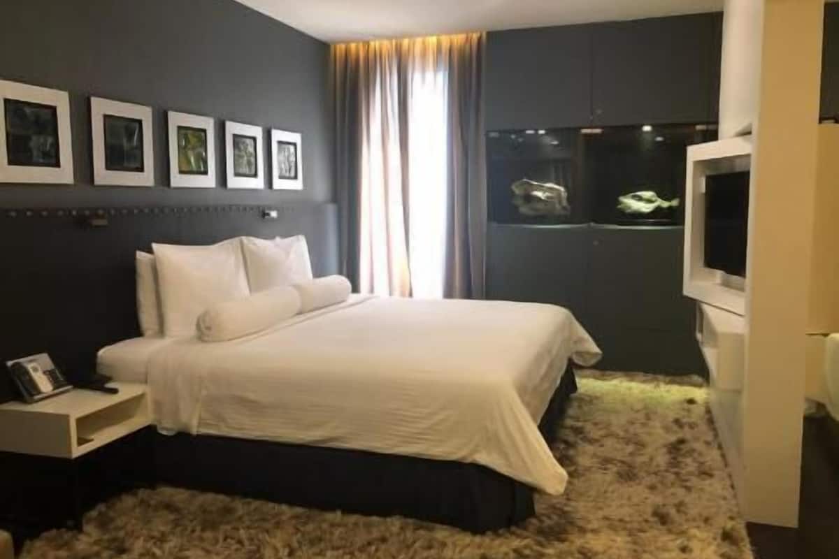 A bedroom with a bed, a nightstand, a TV, and framed pictures on the wall.