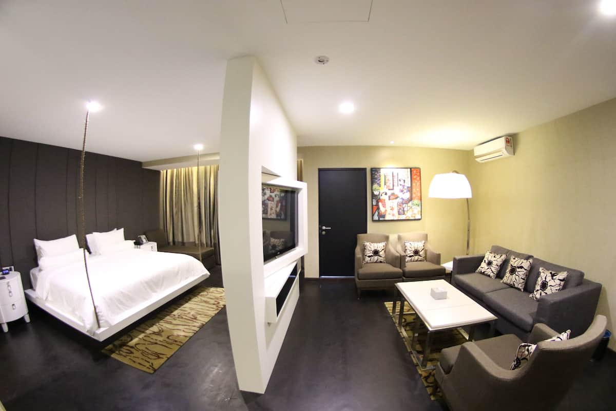 A modern hotel room with a bed, a sofa, a TV, and a desk.