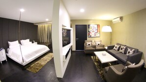 A modern hotel room with a bed, a sofa, a TV, and a desk.