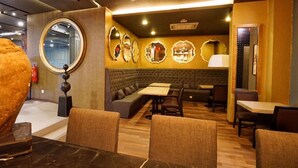 A restaurant with a booth seating area, a round mirror, and a decorative wall with mirrors.