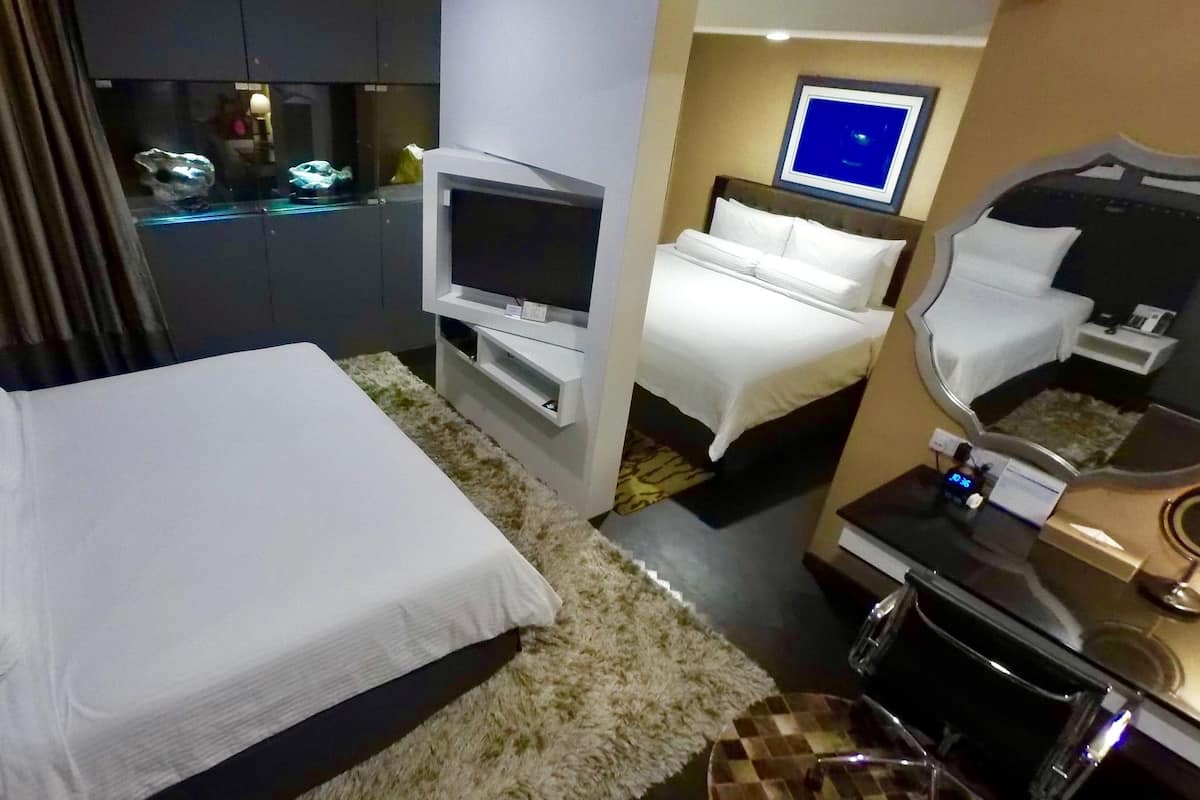A hotel room with a large bed, a TV, a small desk, and a mirror.