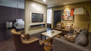 Una habitación de hotel con cama, sofá, mesa de centro y televisión.
