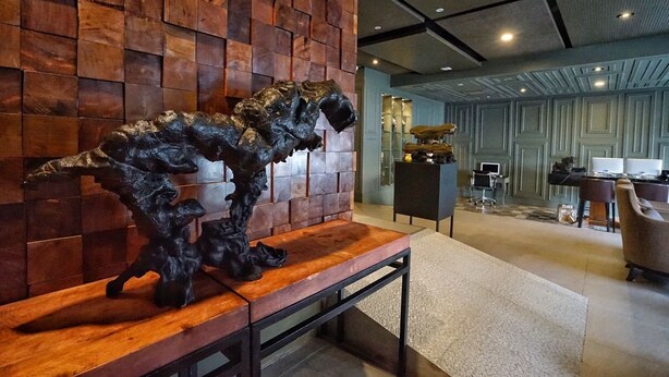 Un interior moderno con una pared de madera, un banco con una escultura y una zona de escritorio con una computadora.