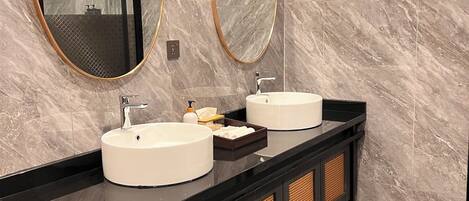 A modern bathroom with two sinks, a large mirror, and a black vanity.