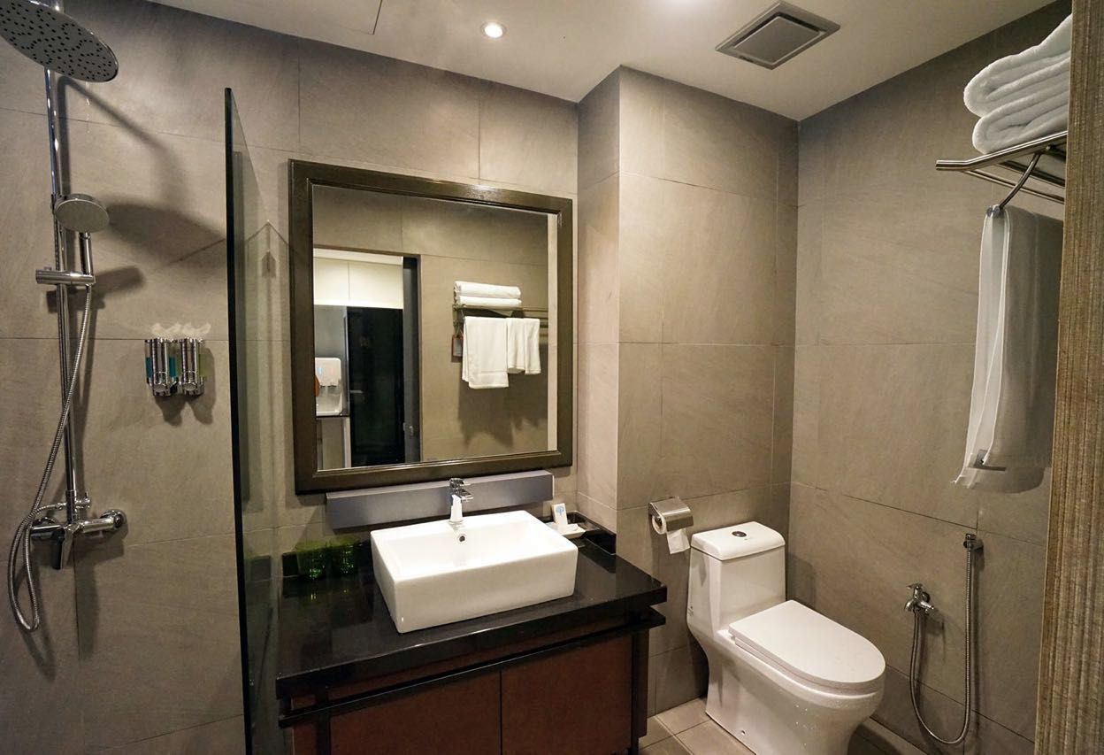 A modern bathroom with a large mirror, a sink, a toilet, and a shower.