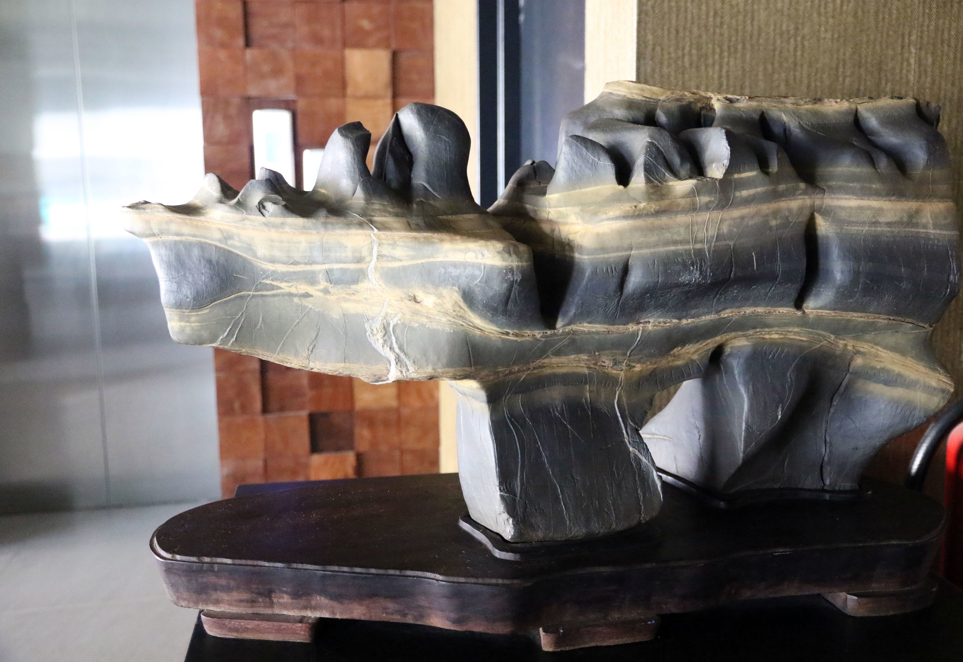 A sculpture of a tree with a textured trunk and branches, placed on a dark wooden base.