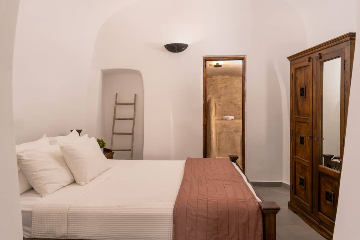 A bedroom with a bed, a wardrobe, and a door leading to a bathroom.