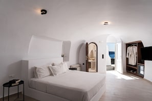 Ein modernes Schlafzimmer mit einem großen Bett, einem Nachttisch, einem Kleiderschrank und Meerblick.