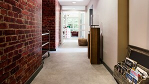Un couloir avec un mur en briques, un banc en bois et un présentoir à magazines.