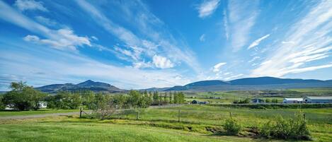 Paisaje rural con cielo despejado, campos verdes y montañas lejanas.