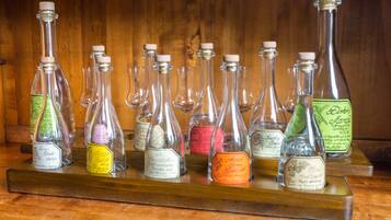 Een houten plank met diverse glazen flessen met etiketten, waarschijnlijk gevuld met verschillende drankjes of sterke drank.