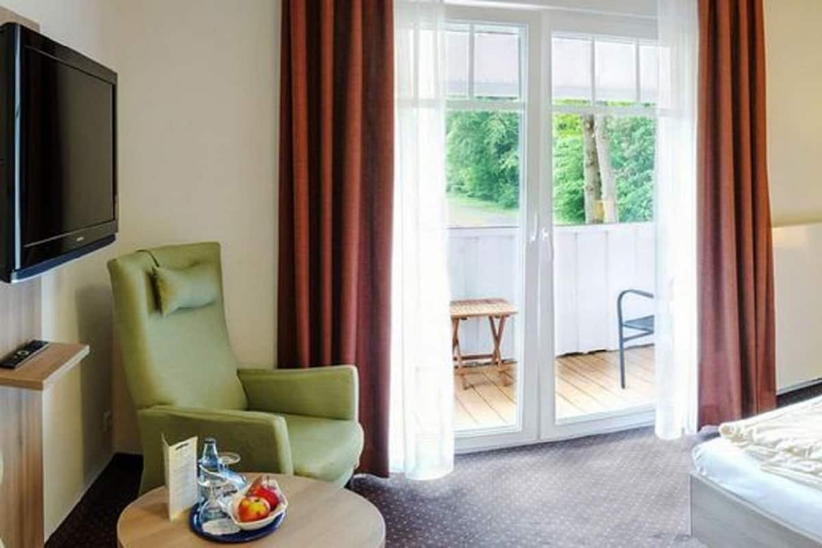 A hotel room with two beds, a TV, a chair, and a table with a tray of fruit.
