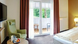 Une chambre d’hôtel avec deux lits, une télévision, une chaise et une table sur laquelle se trouve un plateau de fruits.