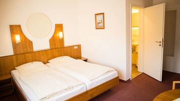 A double bed with a wooden headboard, two bedside tables, a round mirror, and a small framed picture on the wall.