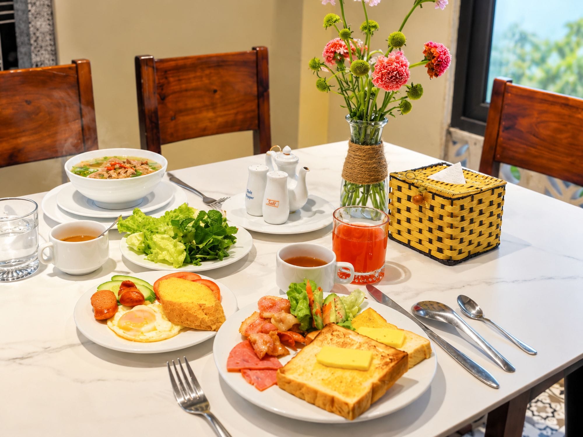 Ein Frühstückstisch mit verschiedenen Speisen, darunter Eier, Toast und Gemüse, sowie Gewürzen und einer Blumenvase.