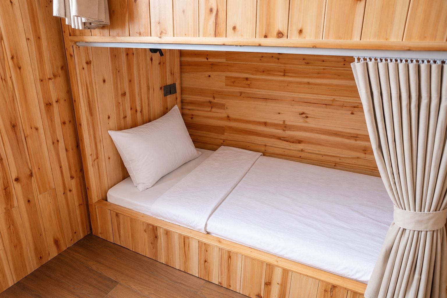 A wooden bunk bed with a single mattress and a pillow.