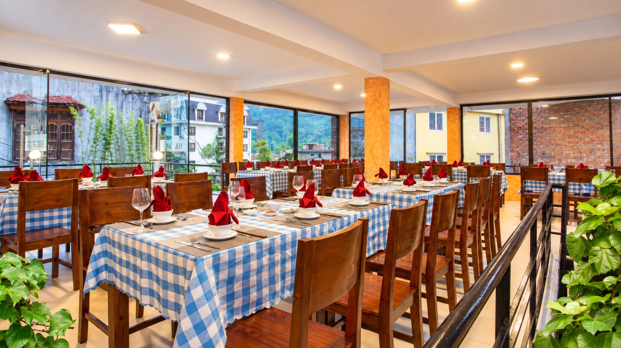 A restaurant with checkered tablecloths, wooden chairs, and red napkins.