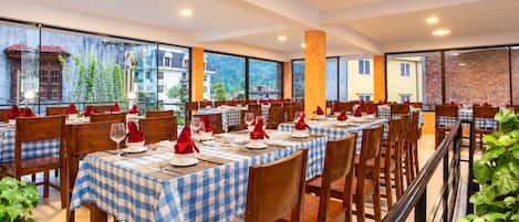 Un restaurante con manteles a cuadros, sillas de madera y servilletas rojas.