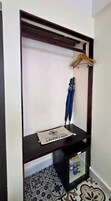 A dark wooden shelf unit with a hanging wooden hanger, a towel, and a laundry bag labeled 'SAPA VILLAGE HOTEL LAUDRY BAG' on the lower shelf.