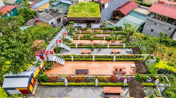 A rooftop garden with a variety of plants and flowers, a small pavilion, and a seating area with benches.