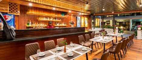 A restaurant with a bar area, multiple tables, and chairs.