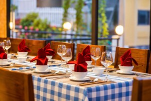 A restaurant table set with white bowls, red napkins, and wine glasses.