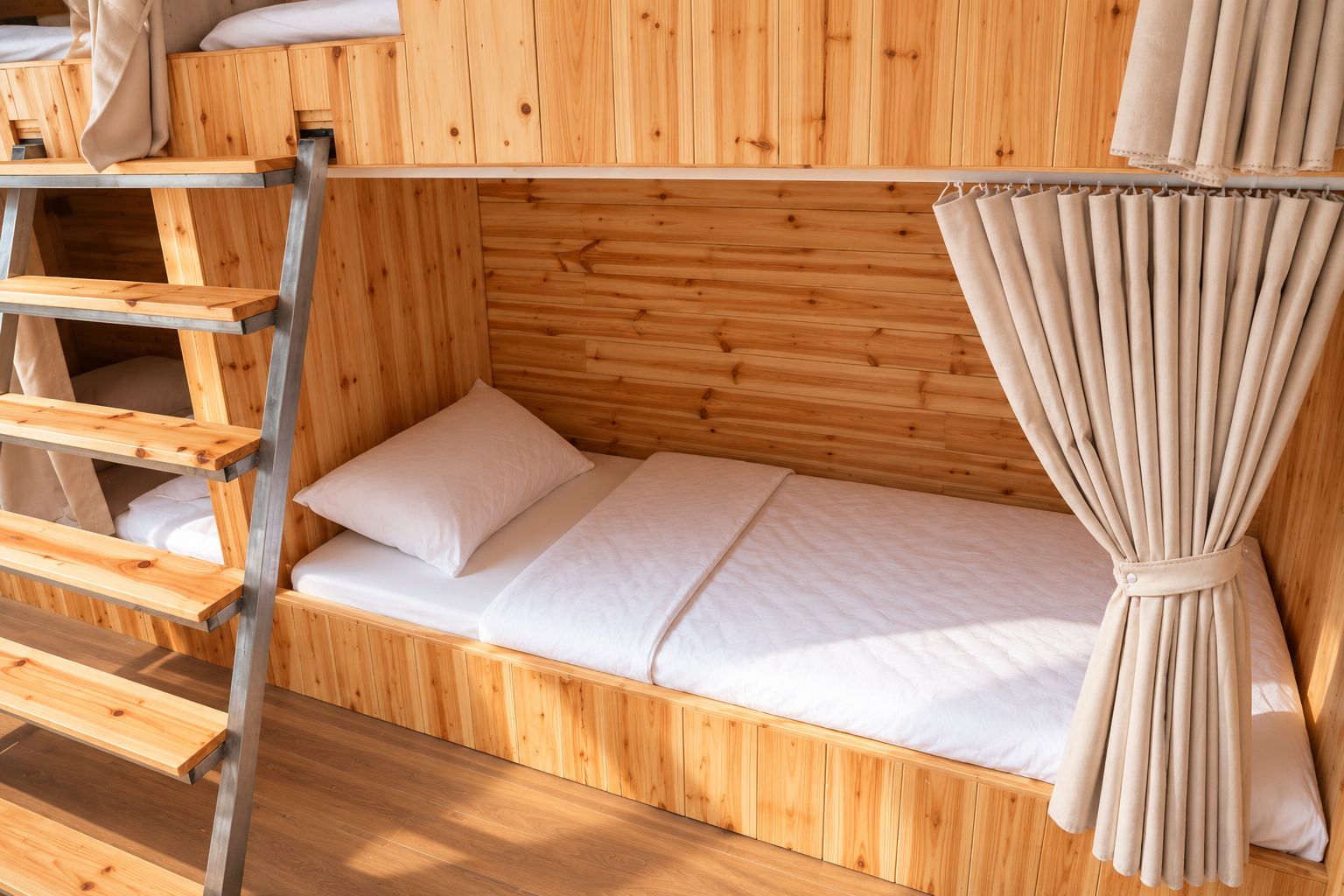 A bunk bed with a ladder, a single bed, and a curtain.
