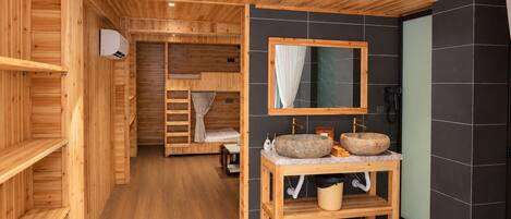 Un intérieur en bois avec une salle de bain comprenant deux vasques en pierre, un miroir et un meuble-lavabo en bois.