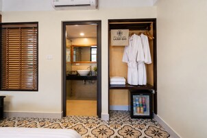 Una habitación de hotel con baño, minibar y perchero para bata.
