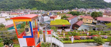Vista de un pueblo con un edificio destacado, techo verde y una estructura colorida con escaleras.