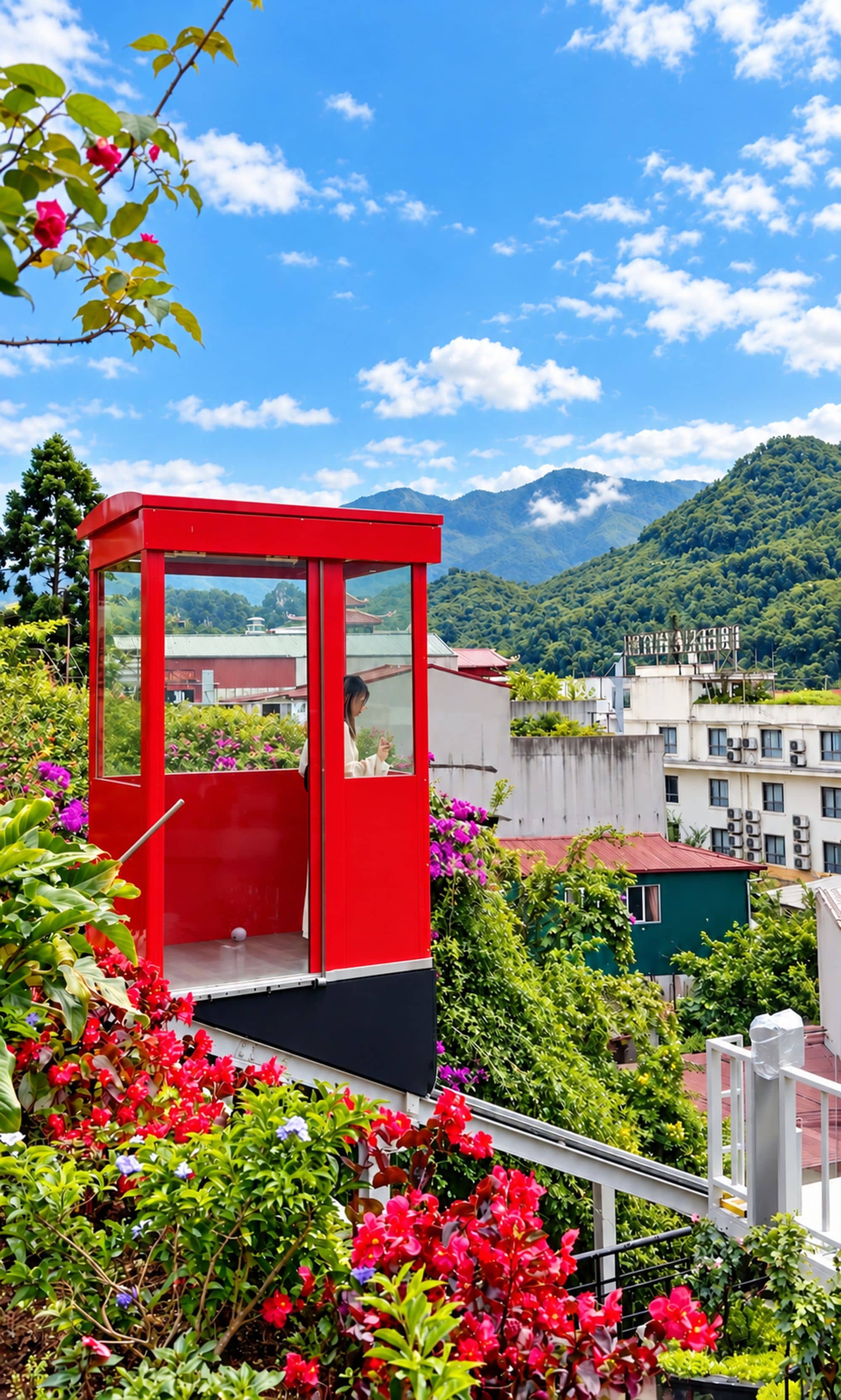 A red cable car with a person inside, surrounded by lush greenery and mountains in the background.