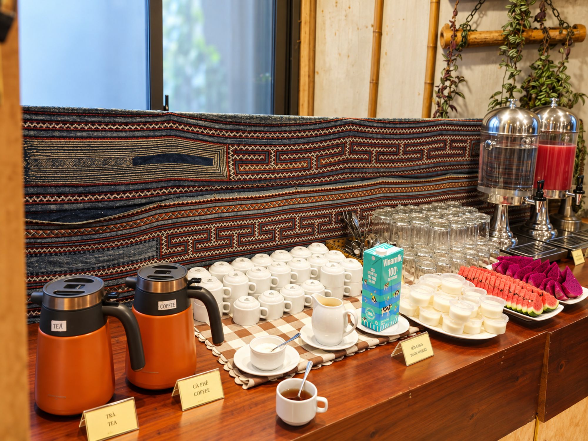 Un bufé de desayuno con café y té, una selección de pasteles y una barra de zumos.
