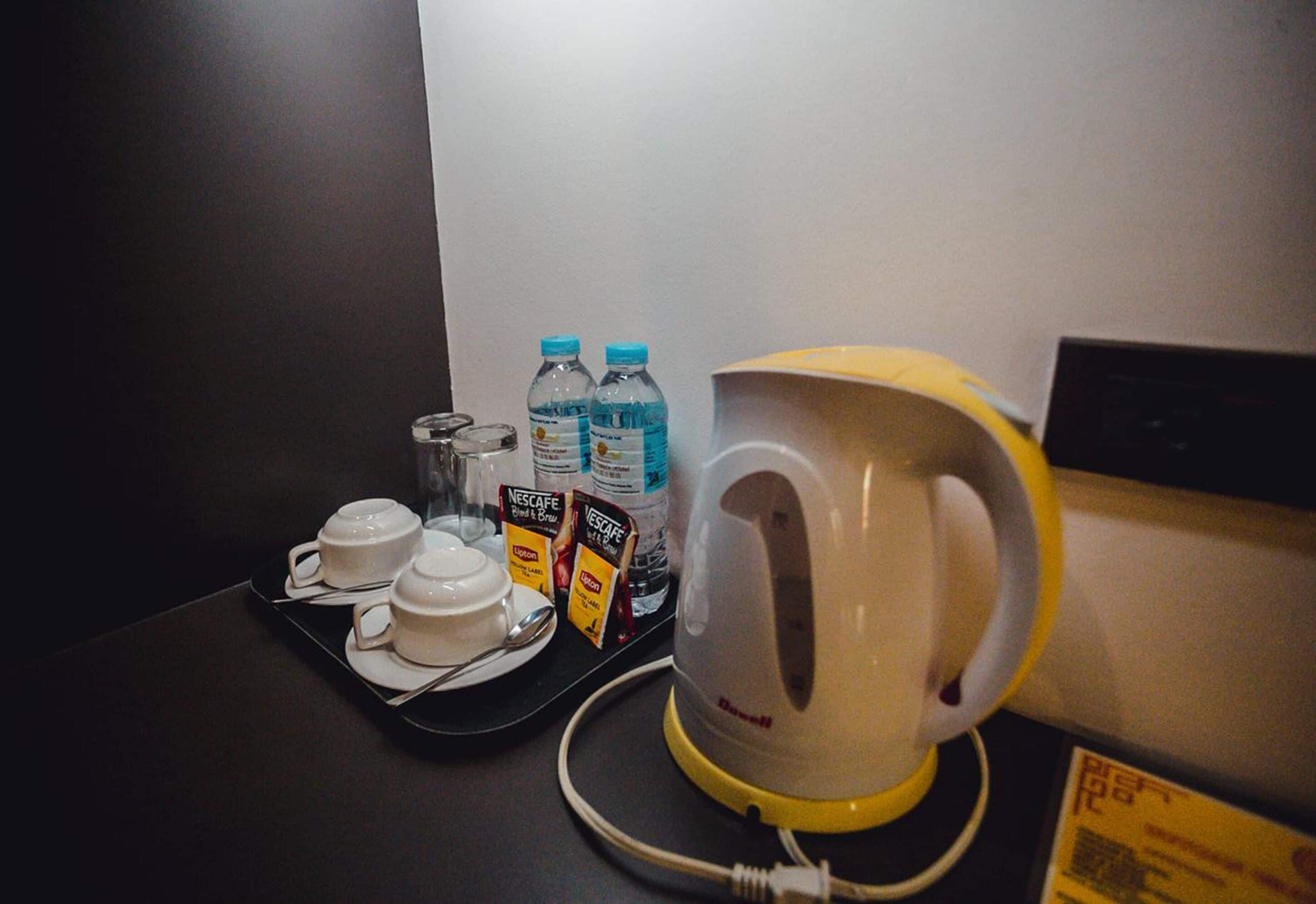 Ett bricka med två vita koppar, två vattenflaskor och två förpackningar snabbkaffepulver från Nescafe, placerat på en mörk yta.