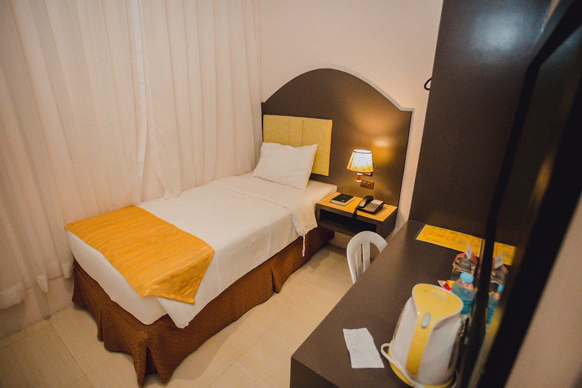 A hotel room with a bed, a nightstand with a lamp, a telephone, and a mirror.