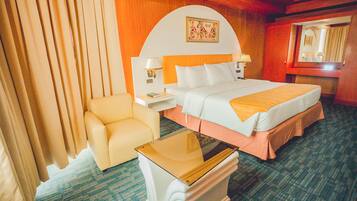 A hotel room with a bed, a chair, a nightstand, and a table.