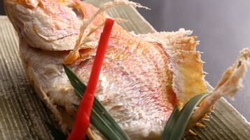 A fish with crispy skin and a red garnish on a textured surface.