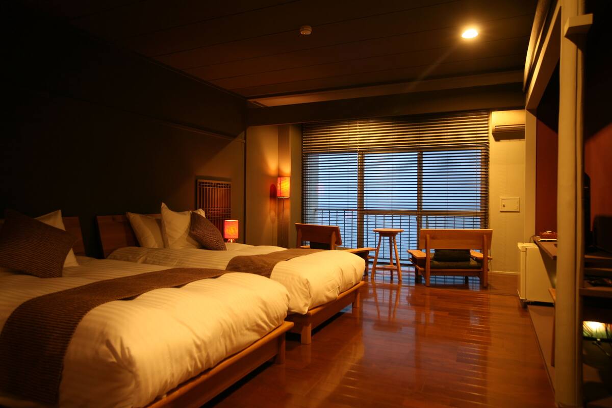 A hotel room with two beds, a desk, and a chair.