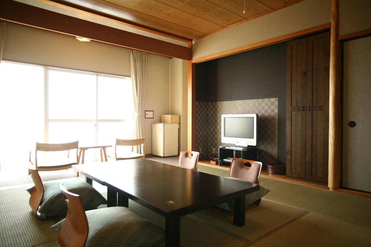 A traditional Japanese-style room with tatami flooring, a low table, and wooden chairs.