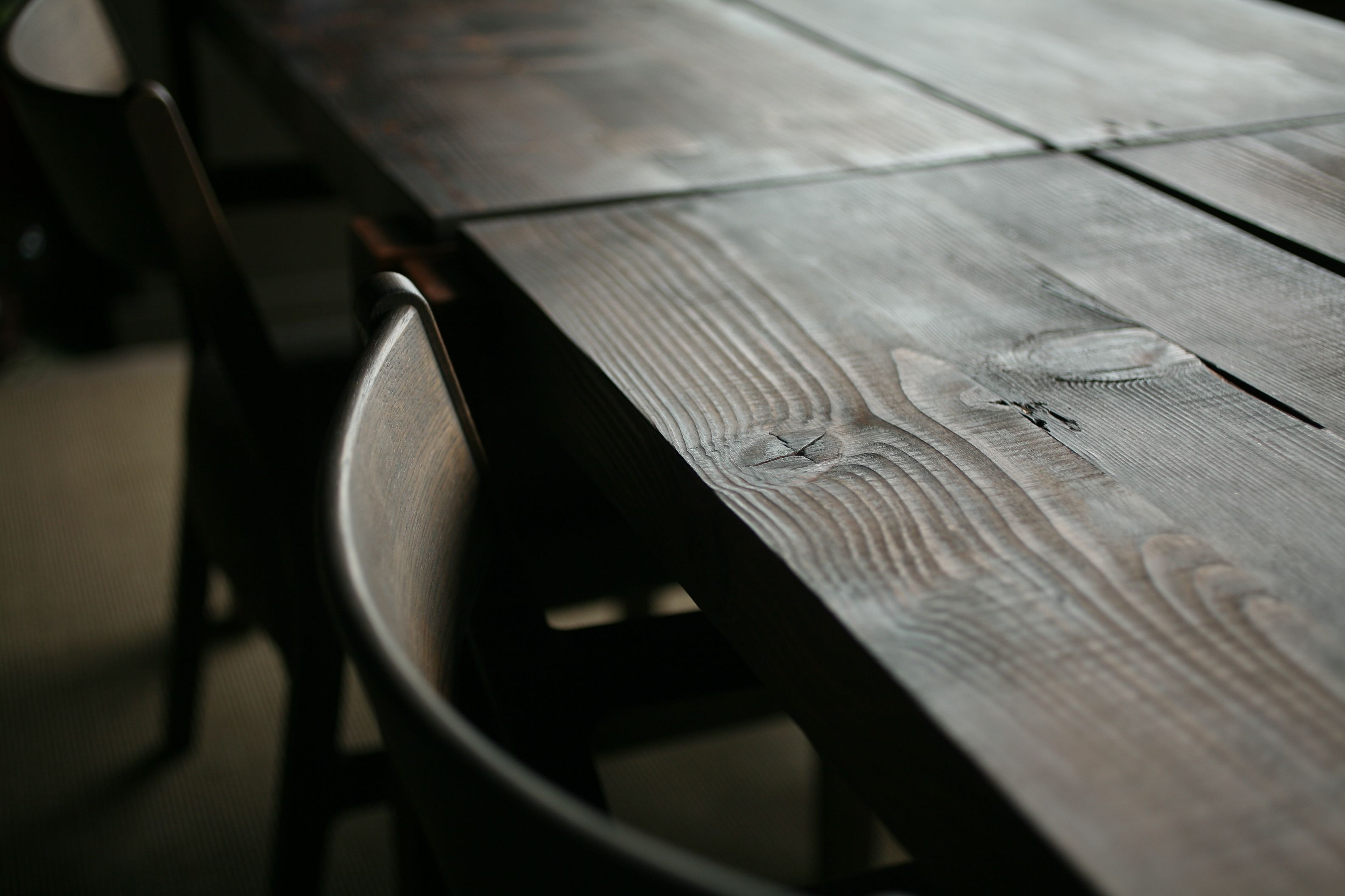 Une table en bois dont on peut distinguer les motifs du grain et une chaise en métal dotée d’un dossier incurvé.