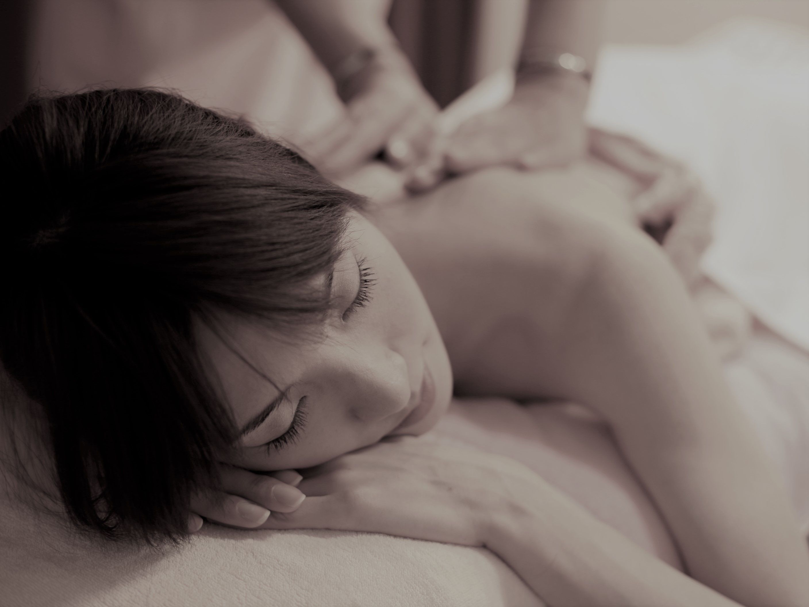 Una persona recostada, posiblemente recibiendo un masaje, con énfasis en la cabeza y la parte superior del cuerpo.