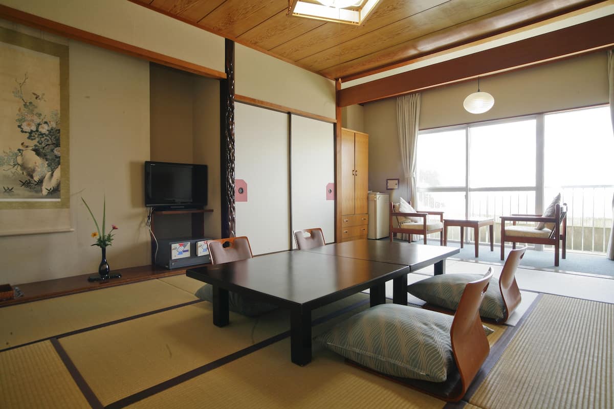 A traditional Japanese-style room with tatami flooring, a low table, and wooden furniture.